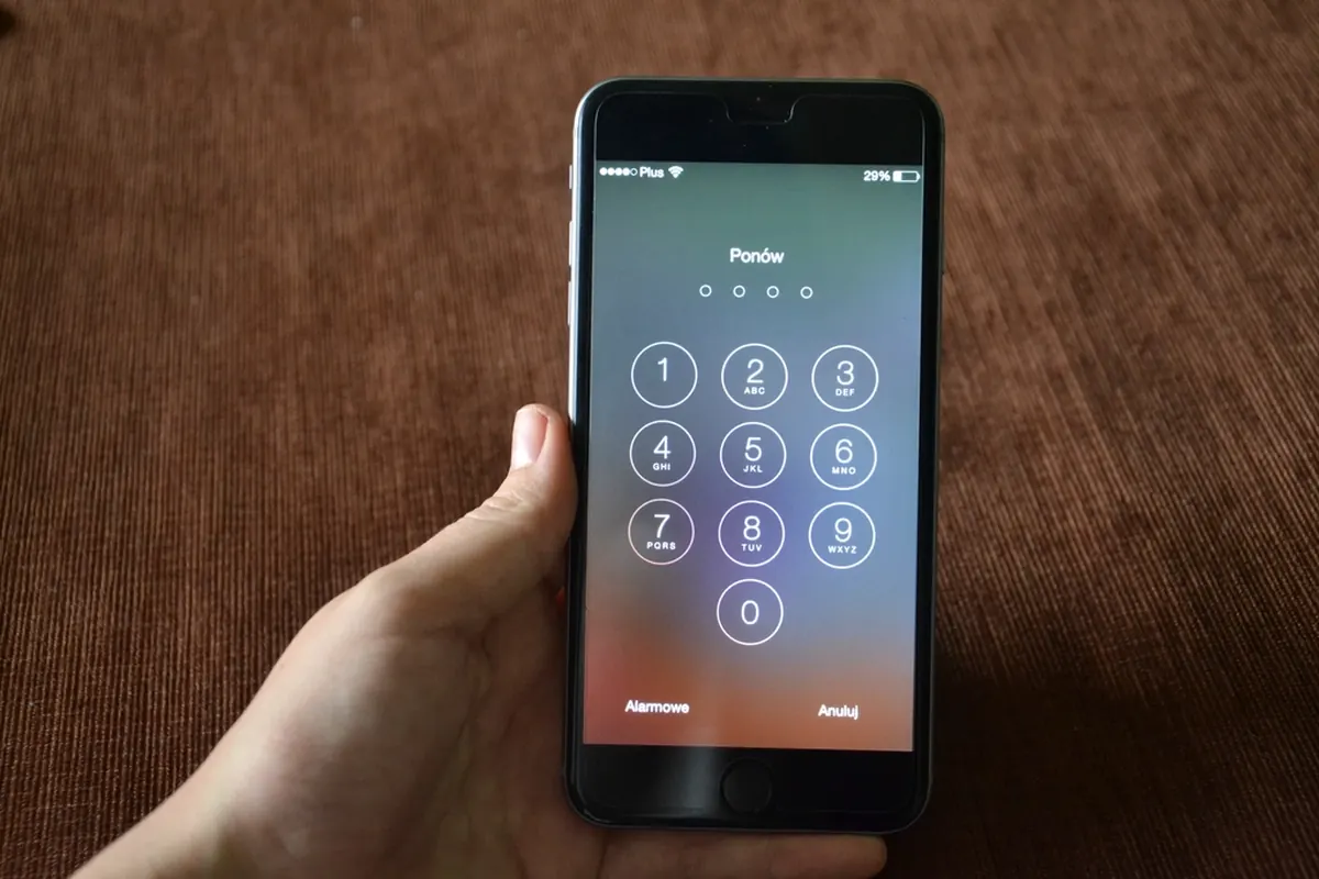 Smartphone passcode screen held in hand, a reminder to use strong passwords