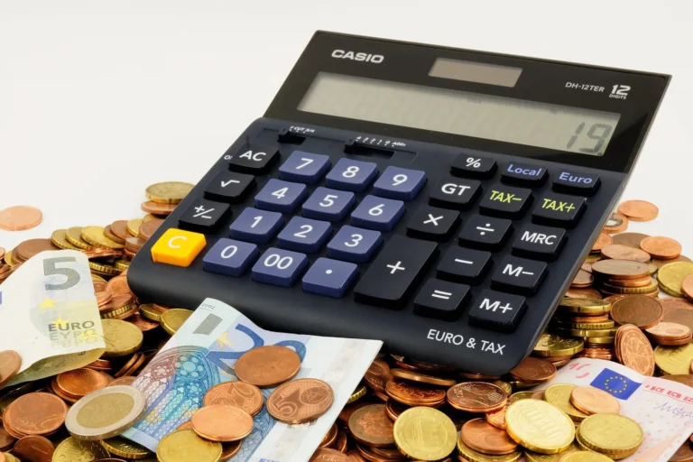 50/30/20 budget rule: calculator on a pile of coins and banknotes