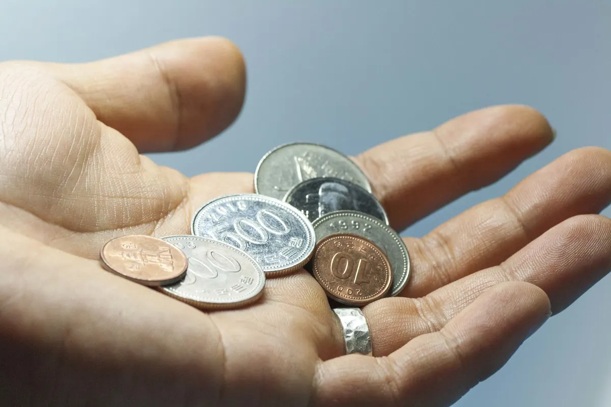 Coins held in an open hand, illustrating how the 50/30/20 budget rule splits income