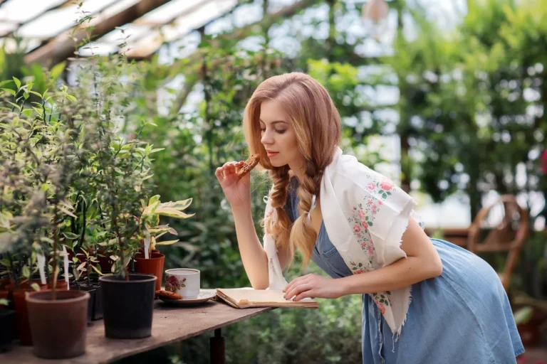 Woman reading a book at a table among plants, building a daily reading habit