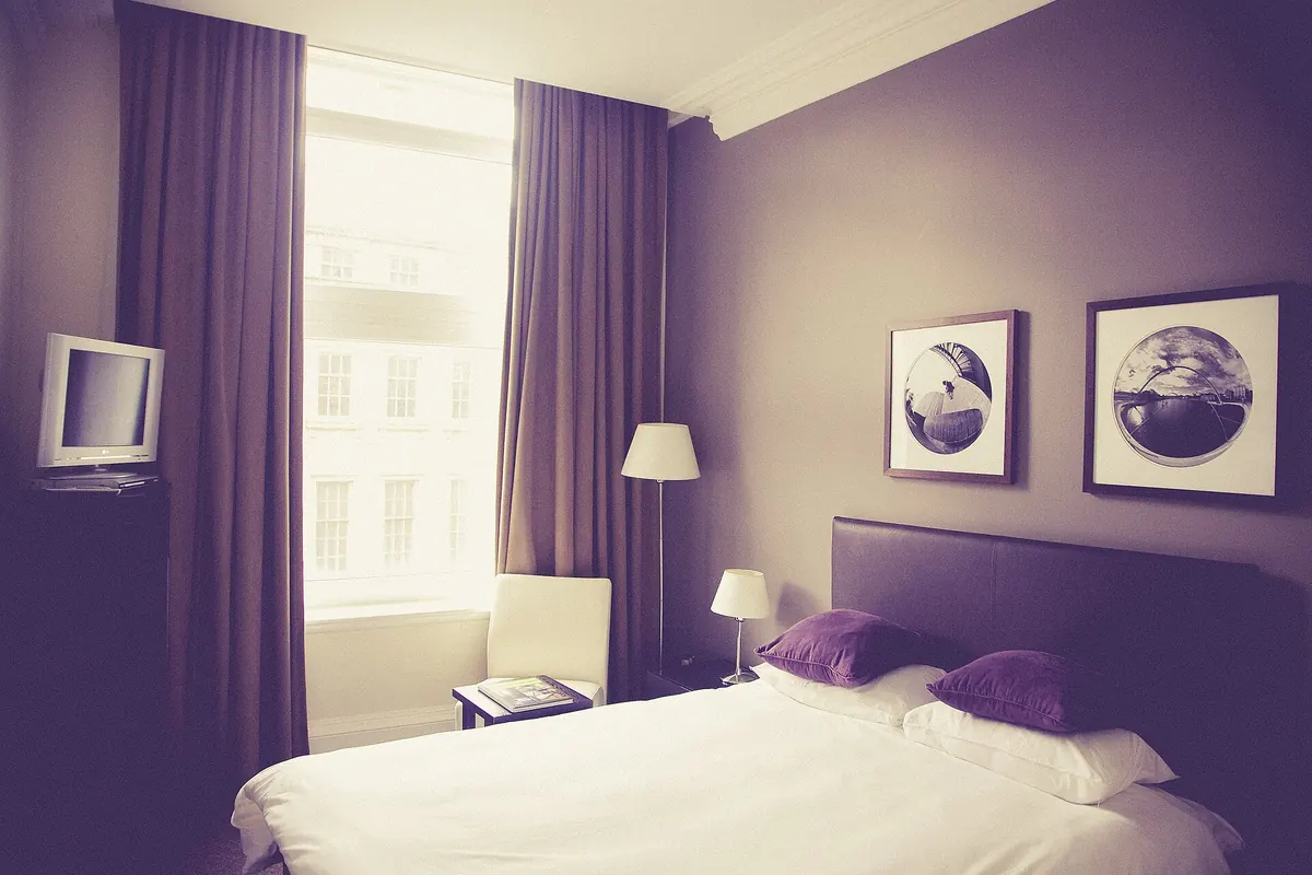Calm bedroom with heavy curtains and soft bedside lamps that help improve sleep quality