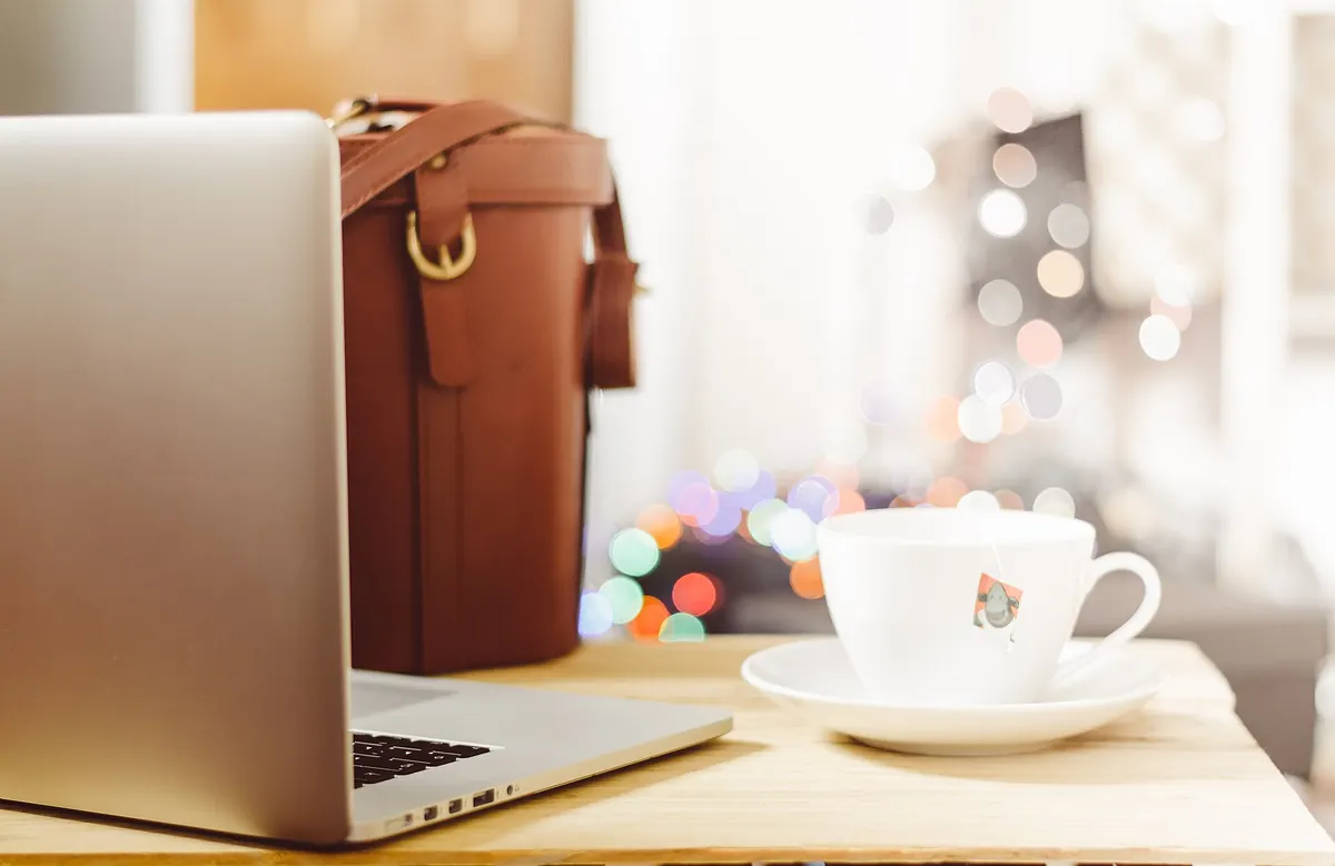 Laptop and cup of tea on a wooden desk in a cozy home office for remote team productivity