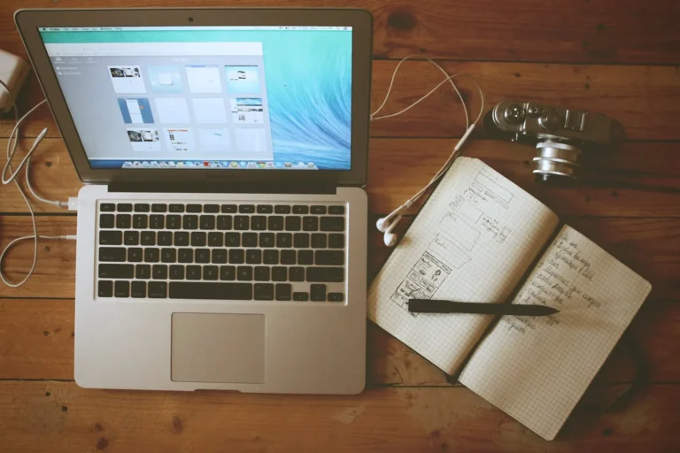 Laptop on a wooden desk next to a notebook, ready to speed up a slow laptop