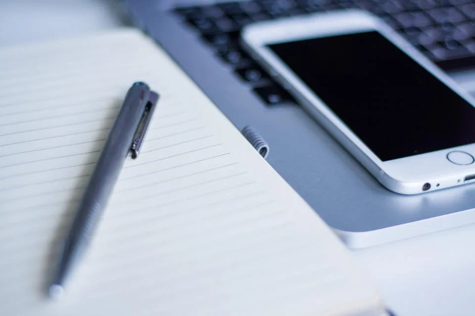 Notebook, pen and smartphone on a desk as the Ztoog.com Editorial Team plans new guides
